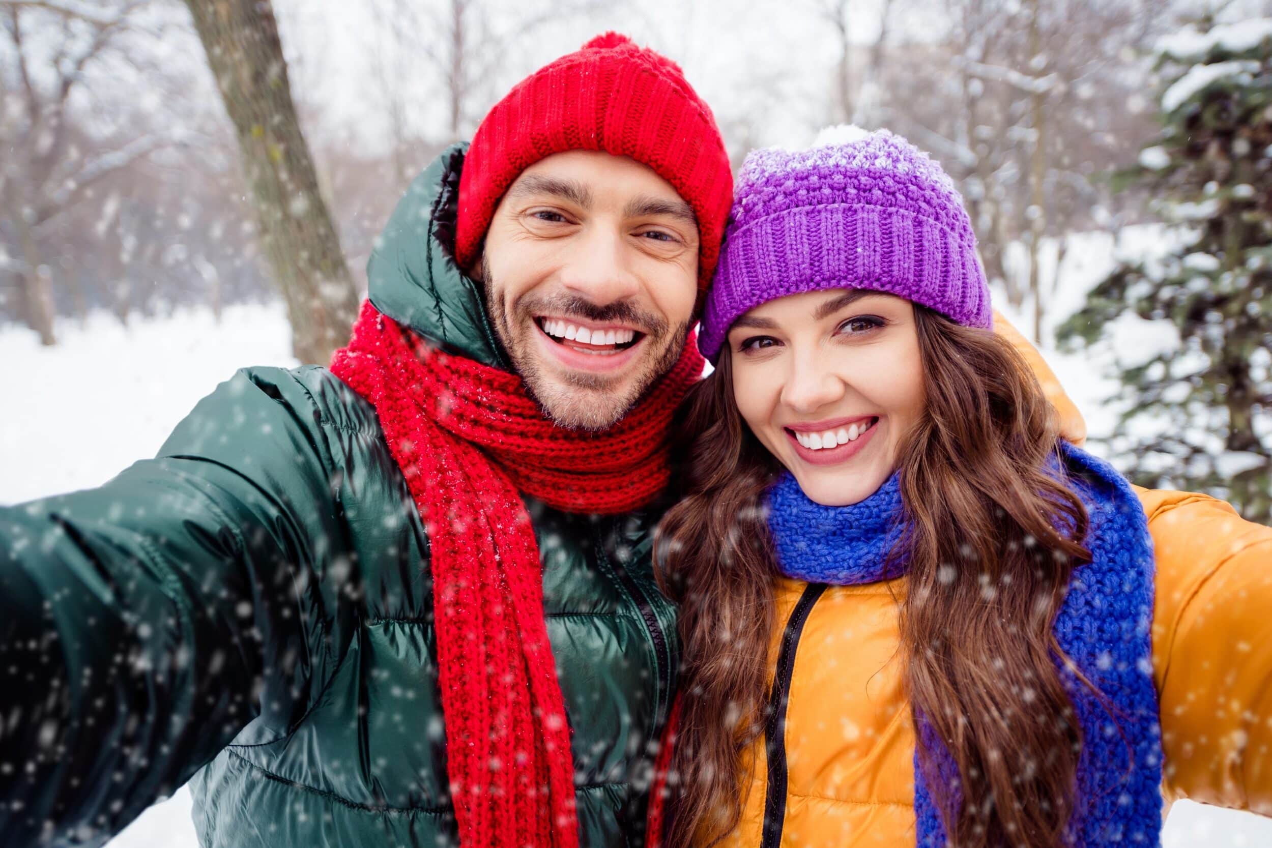Smiling couple taking selfie outdoors during winter vacation, promoting fractional CO2 treatments for skin rejuvenation
