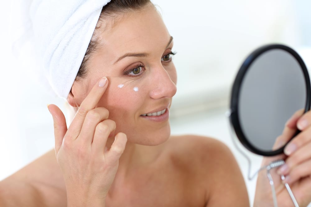 Woman putting on moisturizer after microneedling in Littleton, CO
